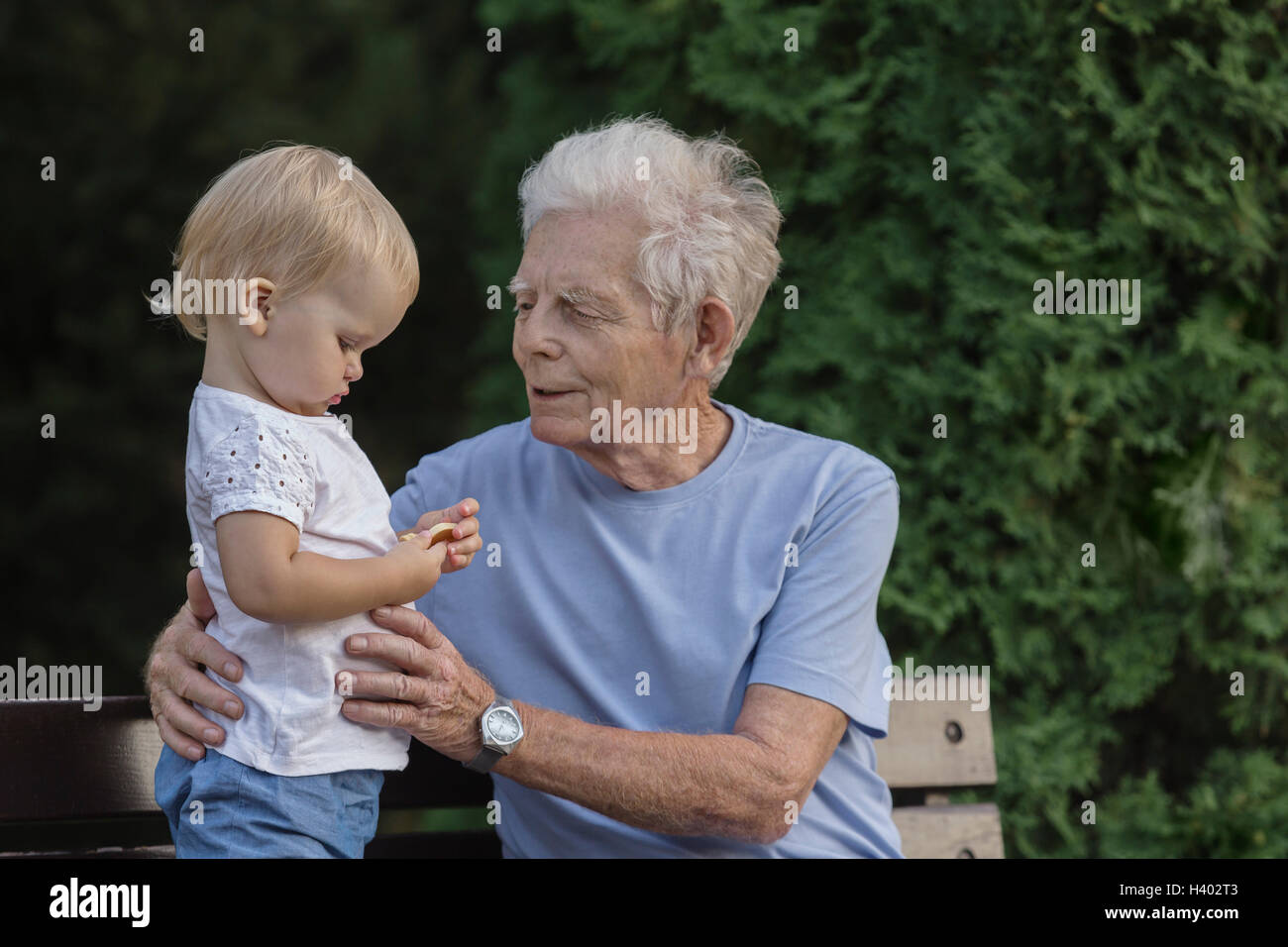 Lächelnden Großvater auf Parkbank mit Mädchen spielen Stockfoto