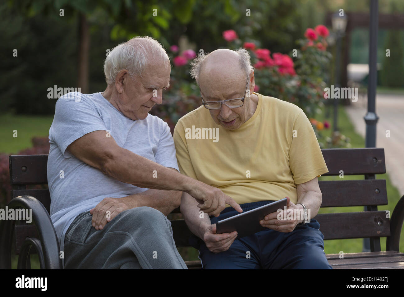 Senior woman zeigen und zeigt Freund auf Parkbank Stockfoto