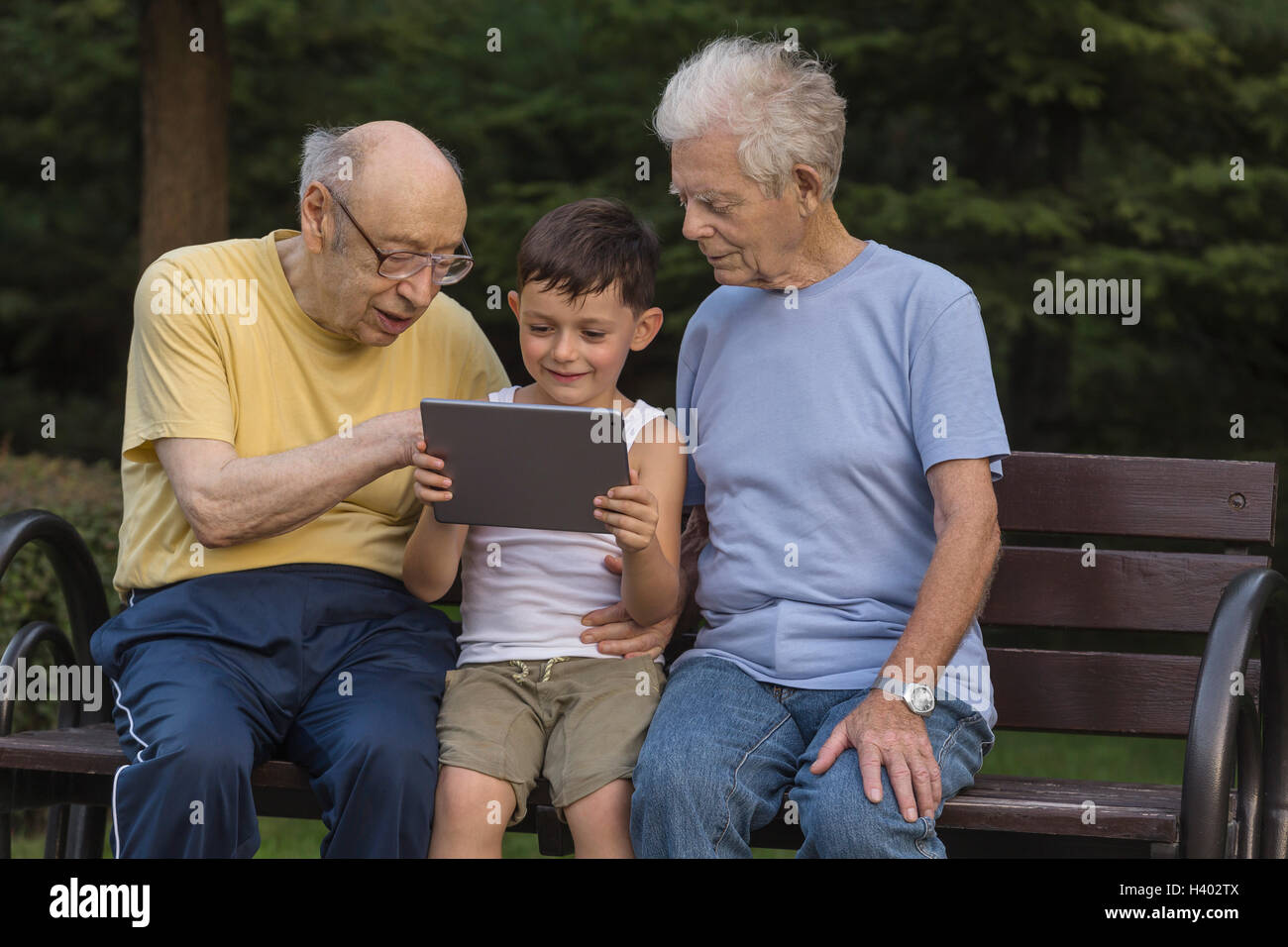 Großväter Blick auf lächelnde junge mit digital-Tablette beim Sitzen auf der Parkbank Stockfoto