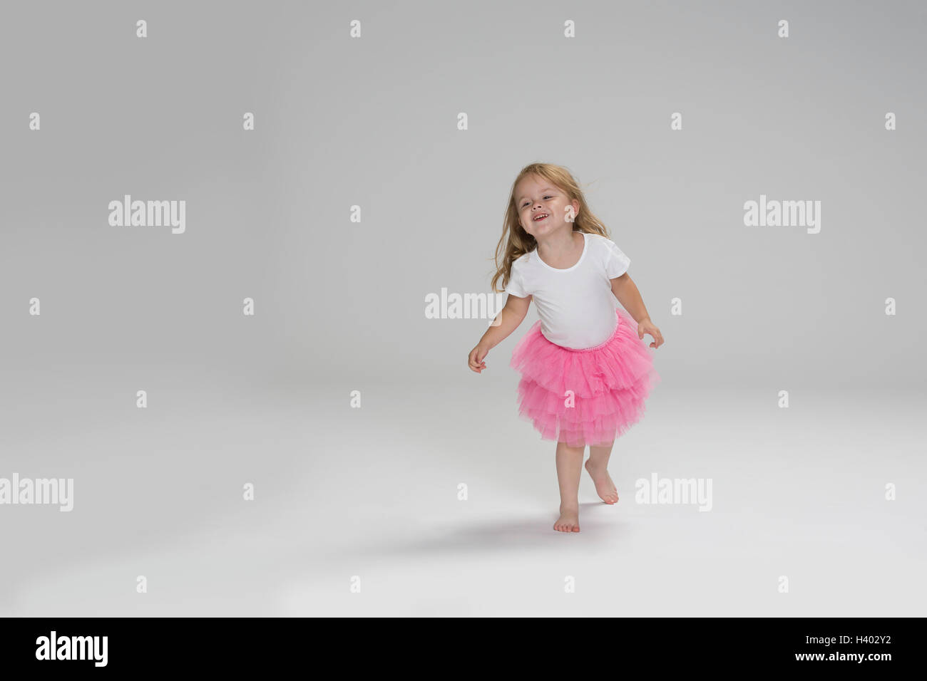 Niedliche Mädchen tragen Tutu spielen gegen grauen Hintergrund Stockfoto