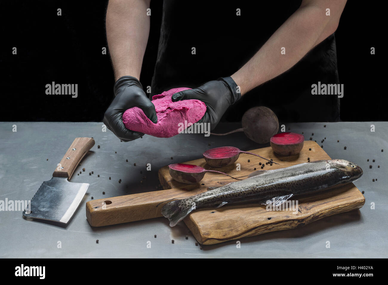 Mittelteil des Mannes rosa Teig zu kneten, rohem Fisch und rote Beete am Tisch Stockfoto