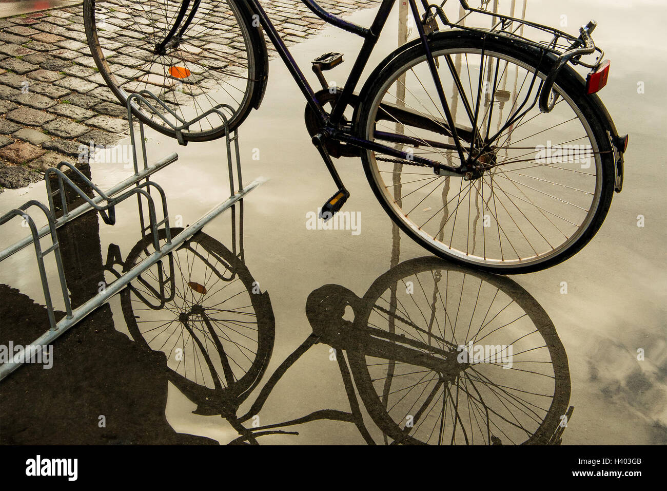 Fahrrad auf Bike Rack Reflexion in Pfütze Wasser abgestellt Stockfoto