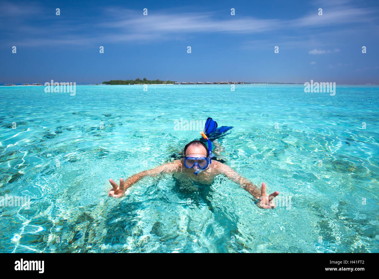Junger Mann Schnorcheln in tropischen Lagune mit über Wasserbungalows Stockfoto