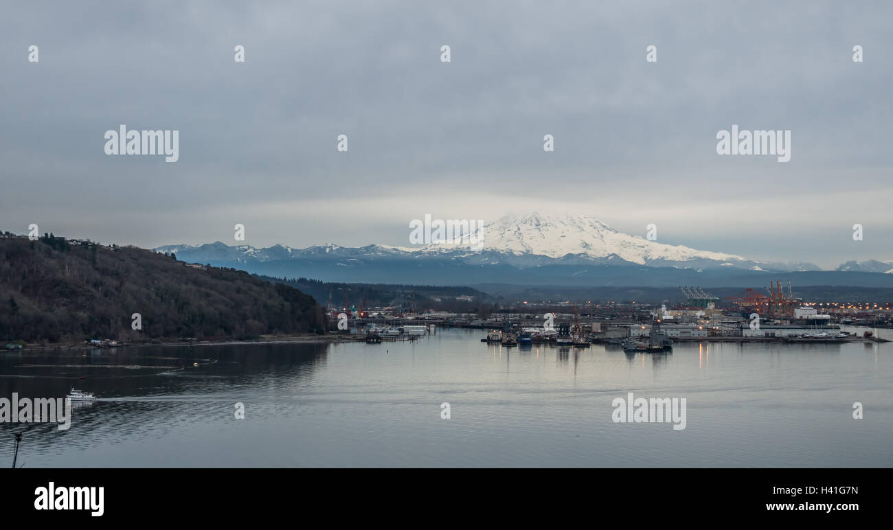 Wolken bedecken den oberen Teil einer Schnee-beladenen Mount Rainier. Port of Tacoma ist unten. Stockfoto