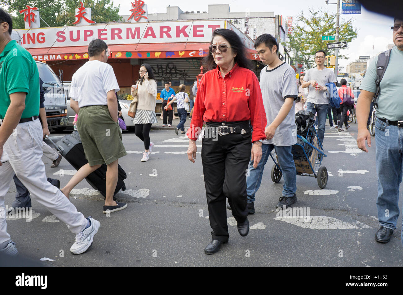Eine Massenszene in Chinatown, Downtown Flushing, New York City mit einer Frau in ein Restaurant im westlichen Stil einheitlich. Stockfoto