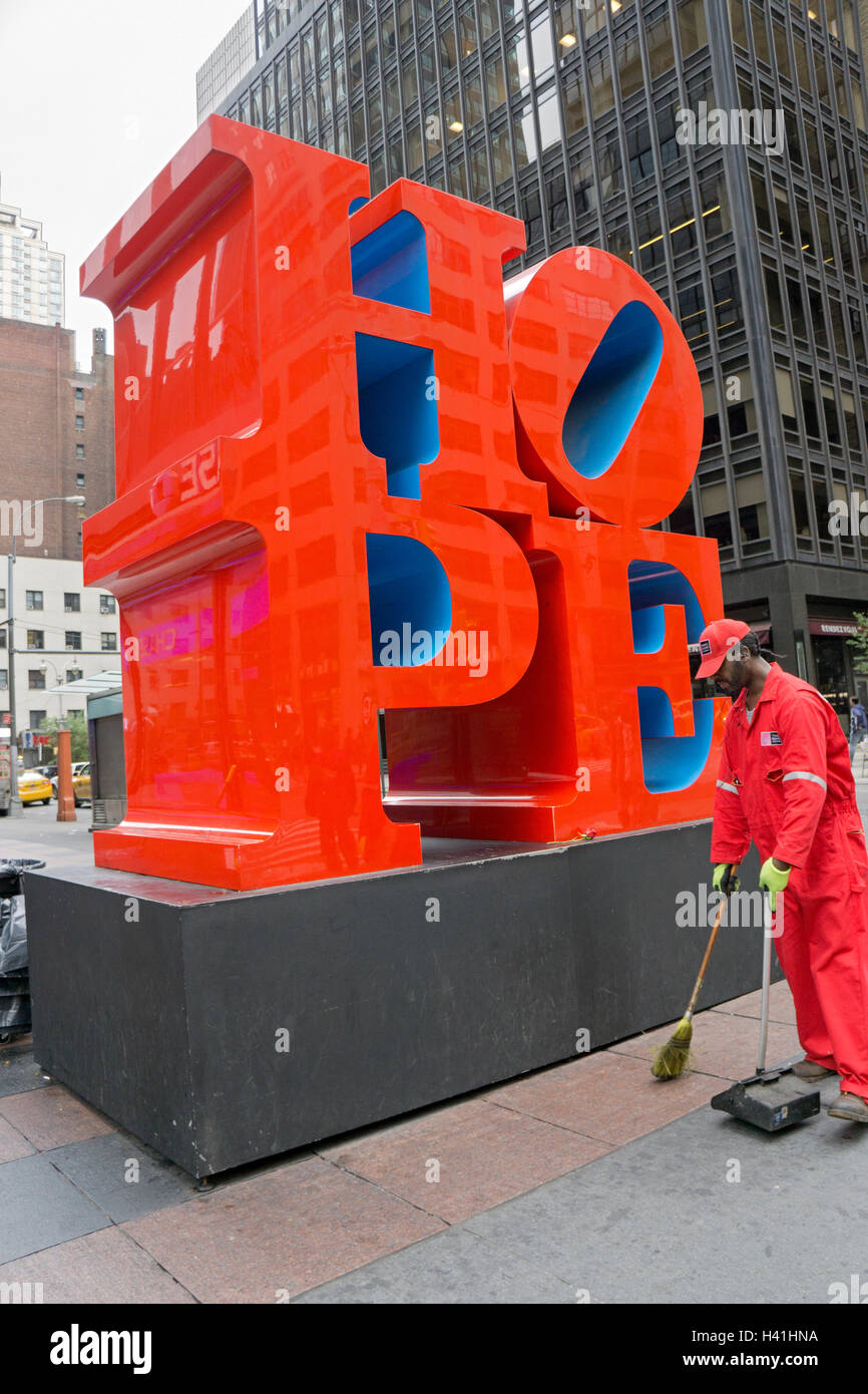 Reiniger Reinigung den Bürgersteig in der Nähe der Hoffnung Skulptur von Robert Indiana auf 7th Ave & 53rd Street in New York City Times Square Straße. Stockfoto