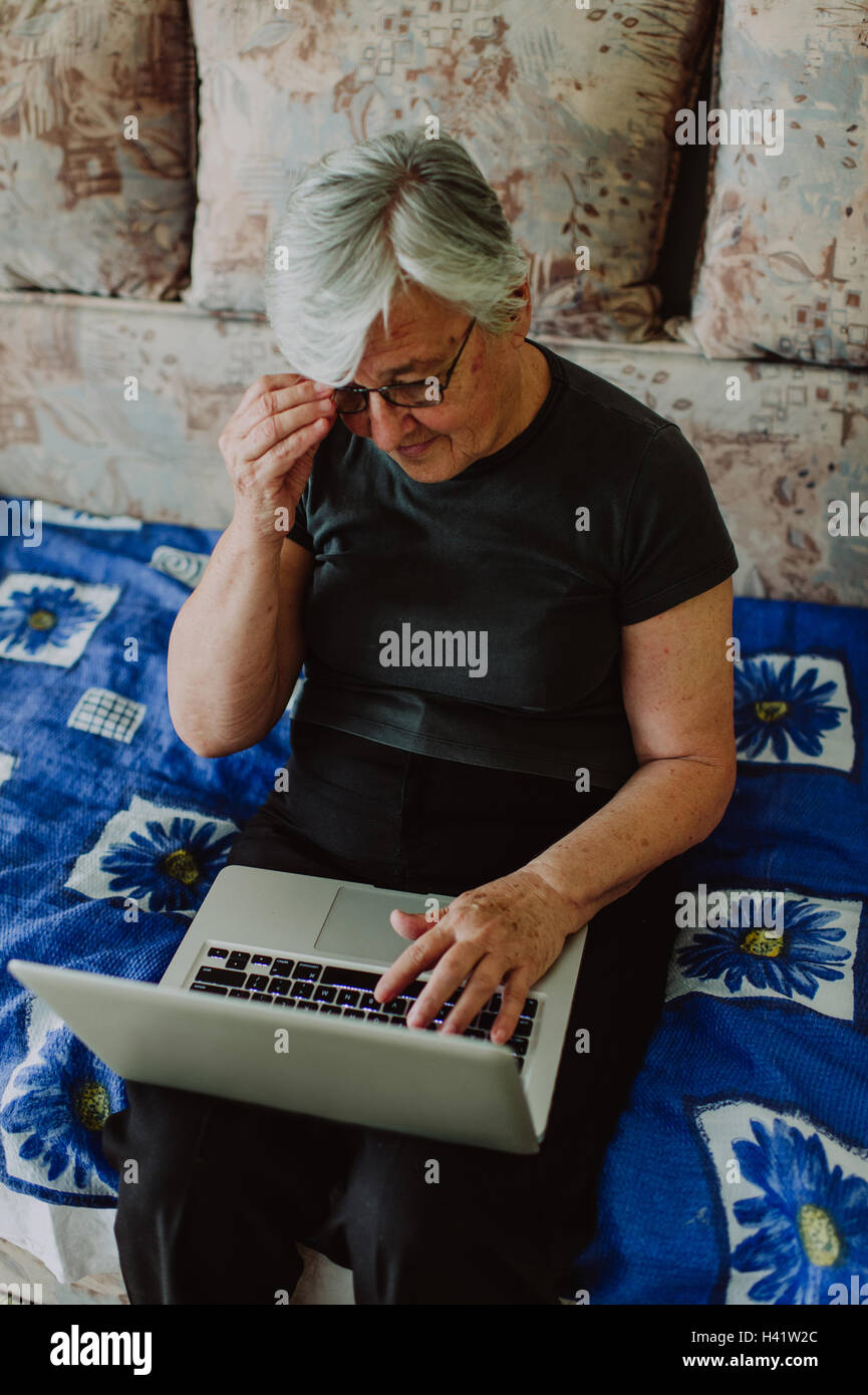 Ältere Frau, die verwirrt während mit einem laptop Stockfoto