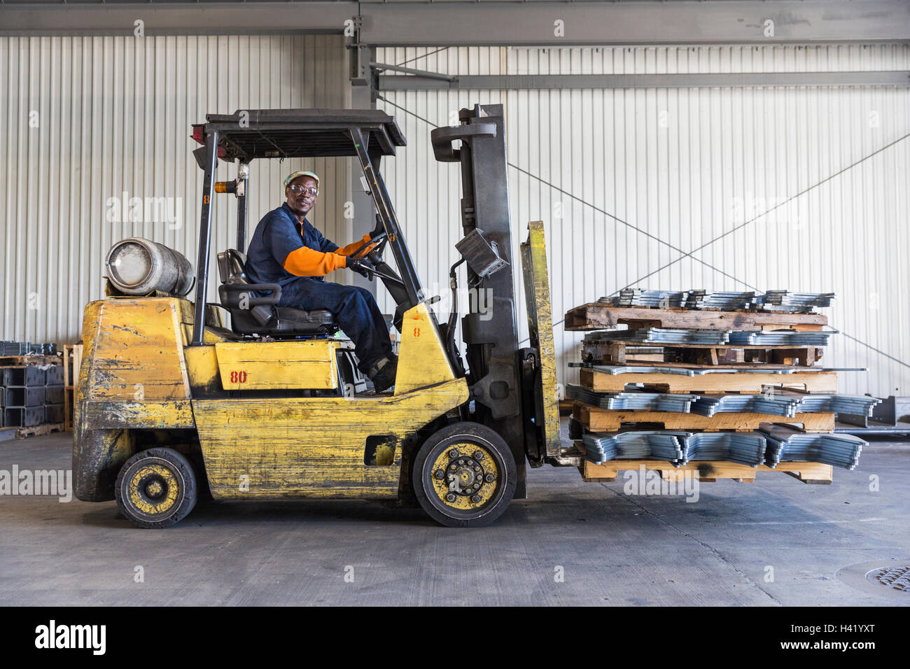 Schwarze Arbeiter fahren Gabelstapler in Fabrik Stockfoto