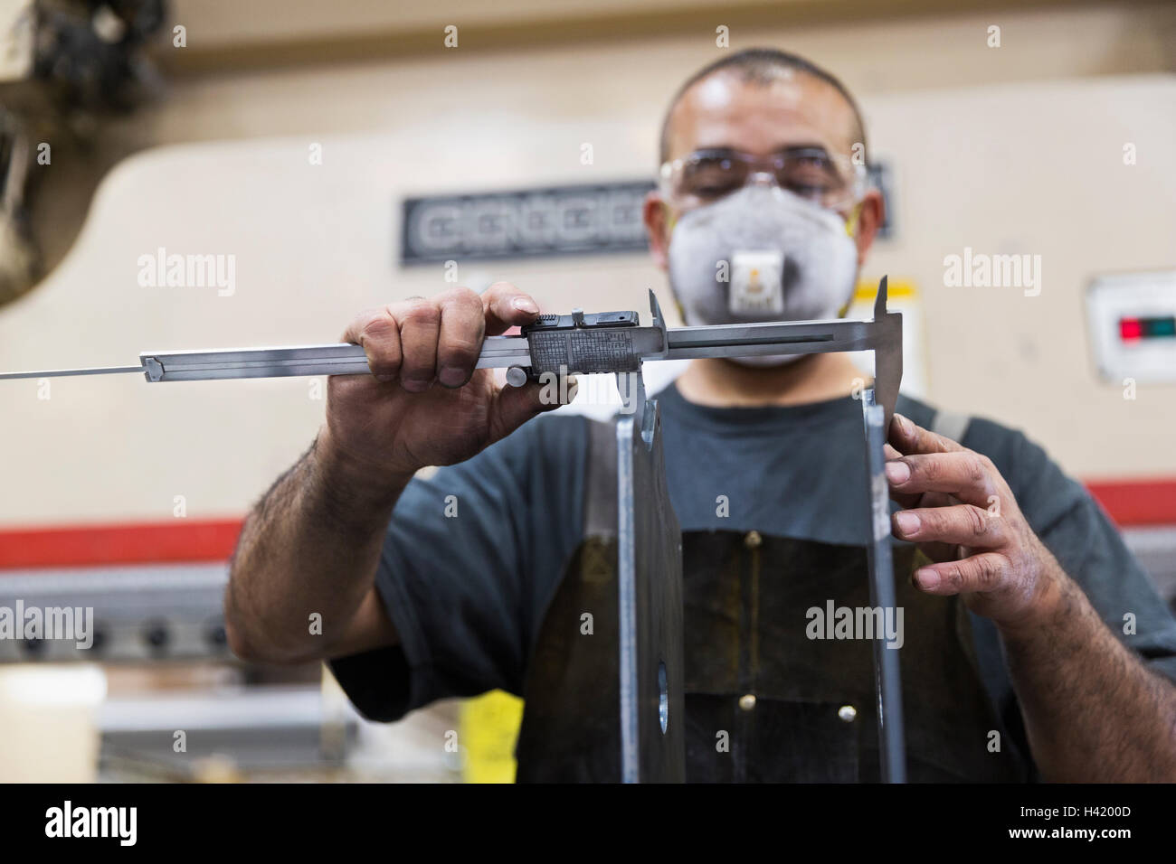 Hispanische Arbeiter Messung Metall mit Bremssattel in Fabrik Stockfoto
