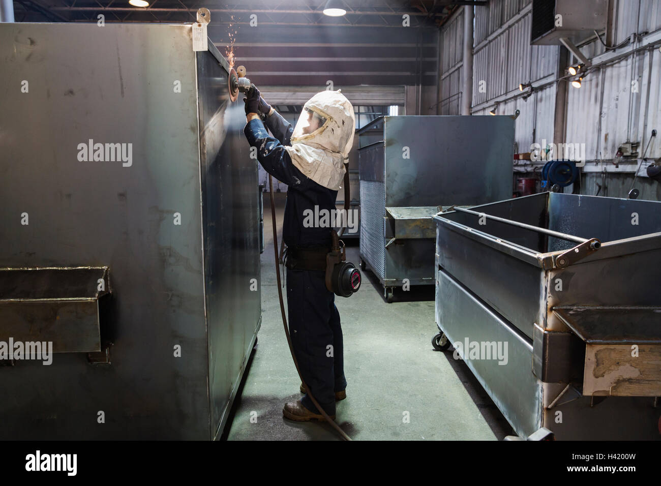 Kaukasische Arbeiter Schleifen Metall-Container in Fabrik Stockfoto