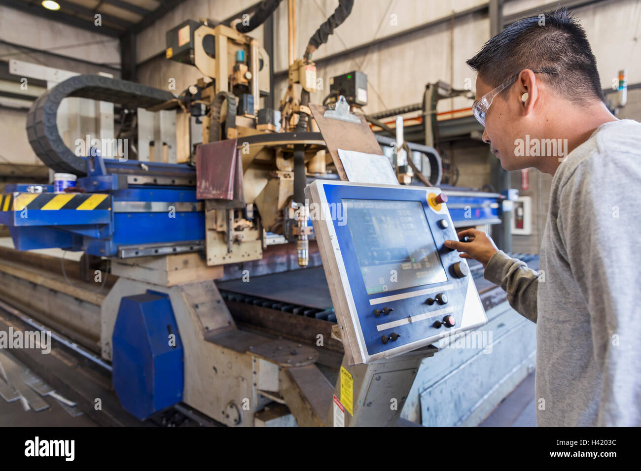 Asiatische Arbeiter über die Systemsteuerung in Fabrik Stockfoto