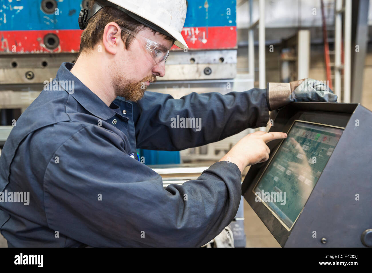 Kaukasische Arbeiter über die Systemsteuerung in Fabrik Stockfoto