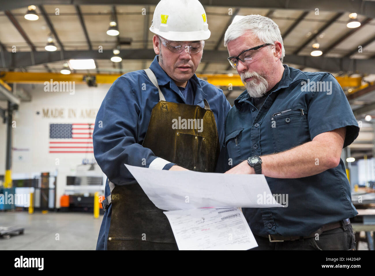 Arbeitnehmer, die Papiere in Fabrik lesen Stockfoto