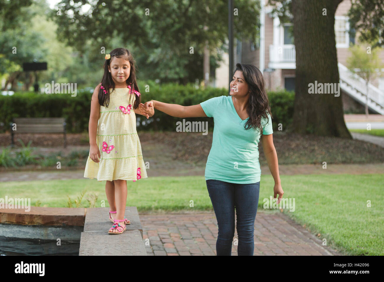 Hispanische Mutter an Hand der Tochter zu Fuß auf Park-Wand Stockfoto