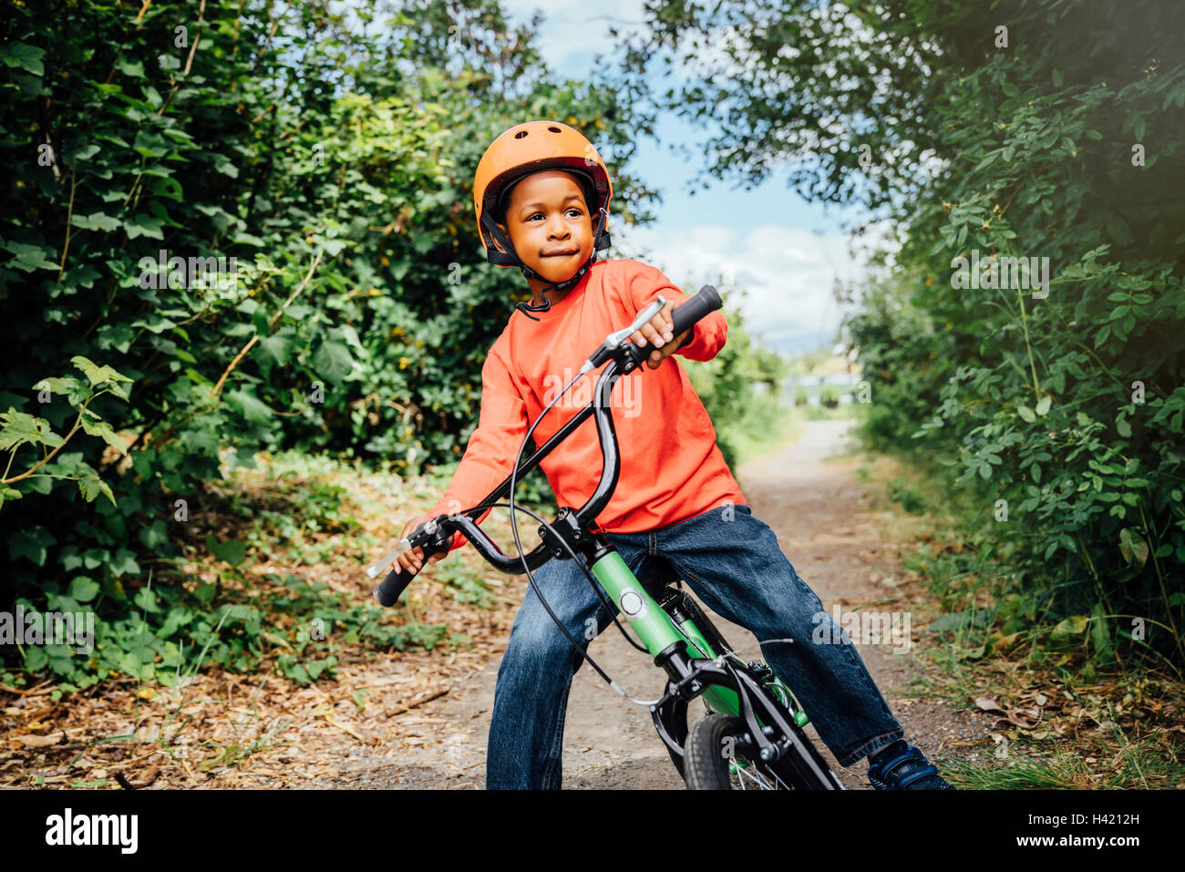 Schwarzer Junge Reiten Fahrrad mit Helm Stockfoto