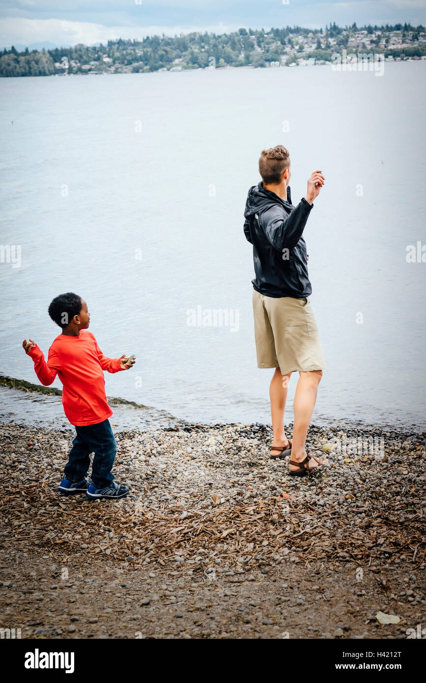 Vater und Sohn werfen von Steinen in Fluss Stockfoto