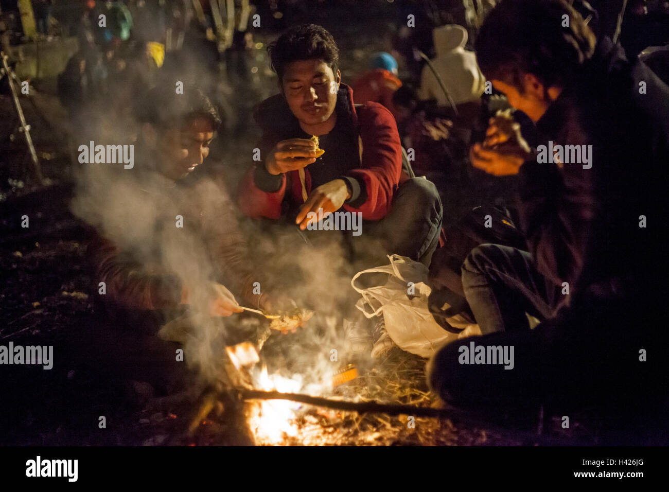 Flüchtlinge mit einem bescheidenen Abendessen in der Nähe von offenem Feuer in die Flüchtlingslager in Spielfeld Stockfoto