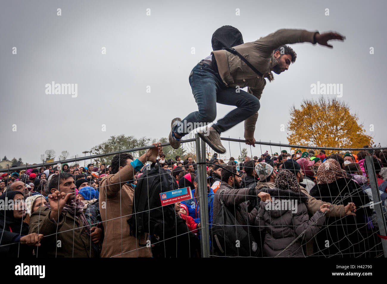 Flüchtling über den Zaun springen, um aus der Zeile für die Slowenisch-österreichischen Grenze in Spielfeld. Stockfoto