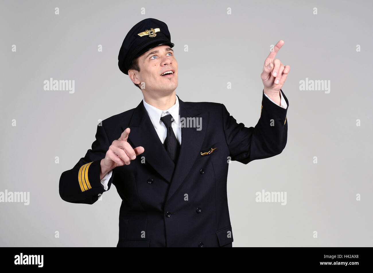 Pilot, jung, Uniform, Blick auf Spitze, mit Begeisterung, Finger, Punkt, Porträt, Modell veröffentlicht, Mann, Person, Stand, Ansicht, überrascht, einfühlsam, freundlich, Beruf, Traumjob, Kapitän, Luftfahrtpersonal, des Piloten Uniform, Kleidung, Kleidung, Anzug, Krawatte, Kopfbedeckungen, Mütze, Piloten Mütze, Logo, Erfolg, Studio, arbeiten Stockfoto