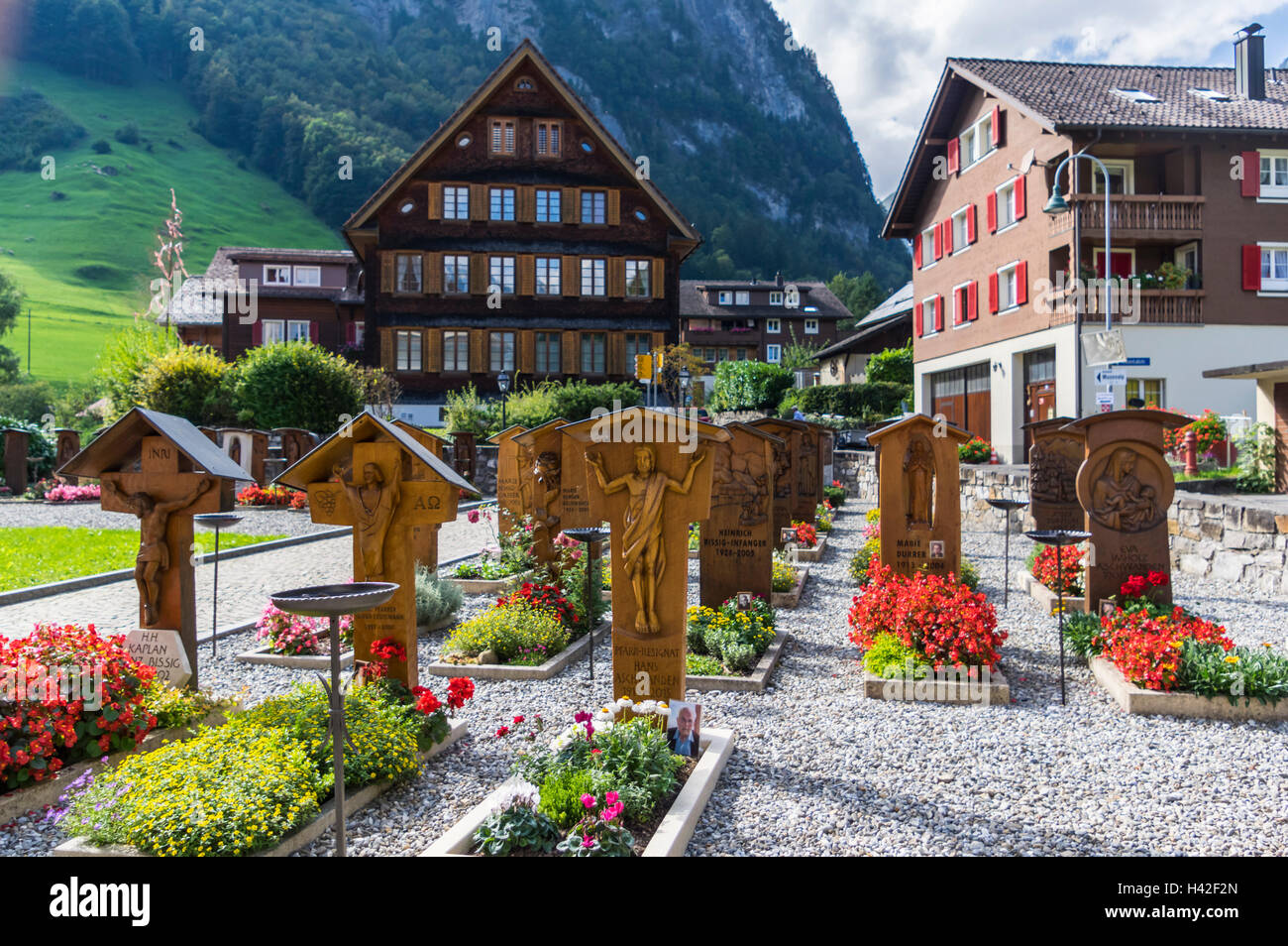 Gebäude und Friedhof Isenthal, einem kleinen Dorf in den Schweizer Alpen. Jedes Grab verfügt über einen geschnitzten hölzernen Grabstein. Kanton Uri, Schweiz. Stockfoto