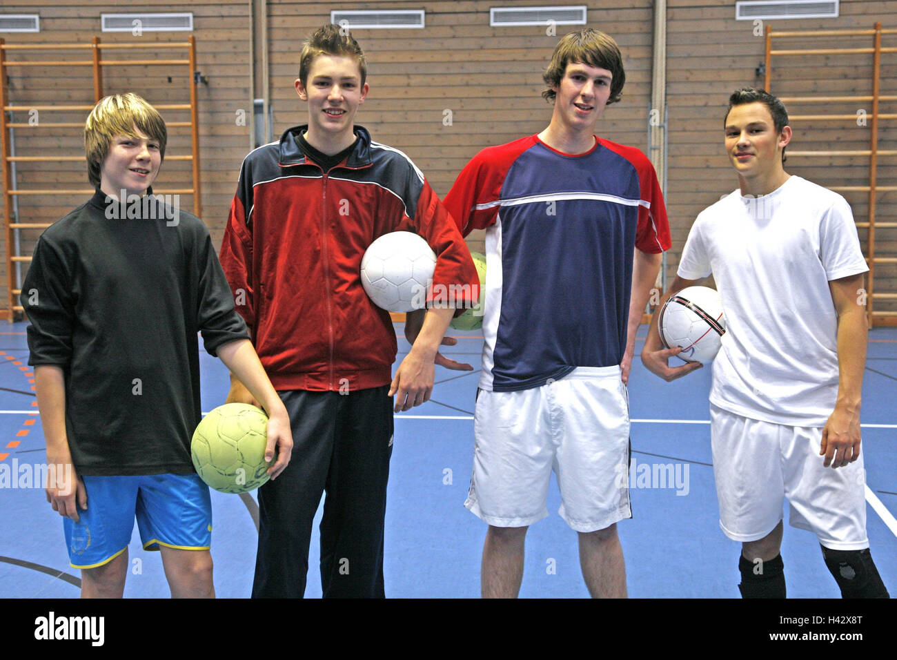 Gymnasium, Teenager, junge, Ständer, Lächeln nebeneinander, Modell veröffentlicht, Schule, Gymnasium, Schule, Sport, Sport, Unterricht, Sportunterricht, Halle Fußball, Fußball, Freunde, Menschen, Schüler, Sportbekleidung, Fußbälle, Kugeln, Fitness, Ausdauer, Konzentration, Freude, körperliches Training, Begeisterung, Stockfoto