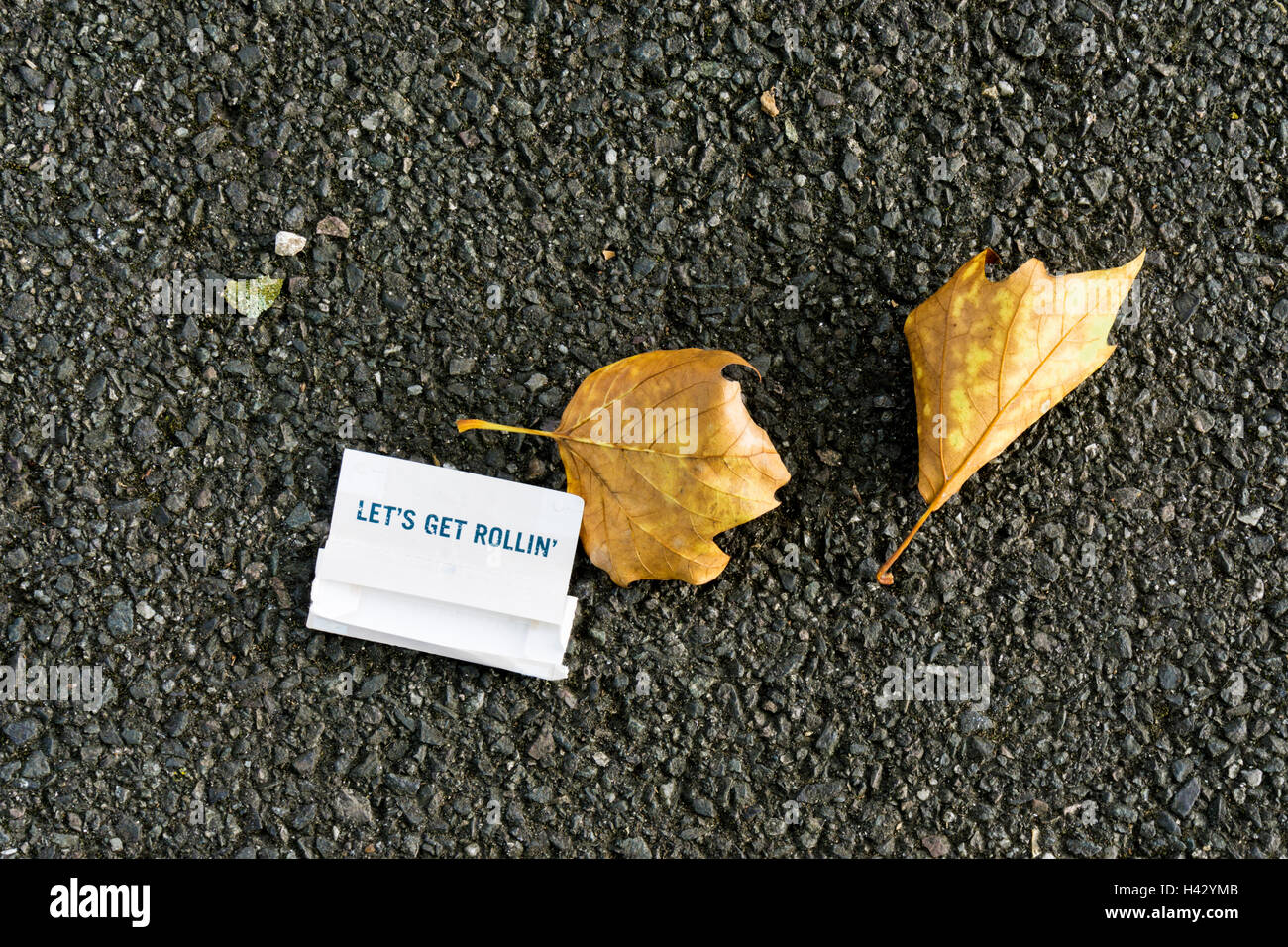 Eine leere Päckchen Zigarettenpapier auf einem asphaltierten Weg. Stockfoto