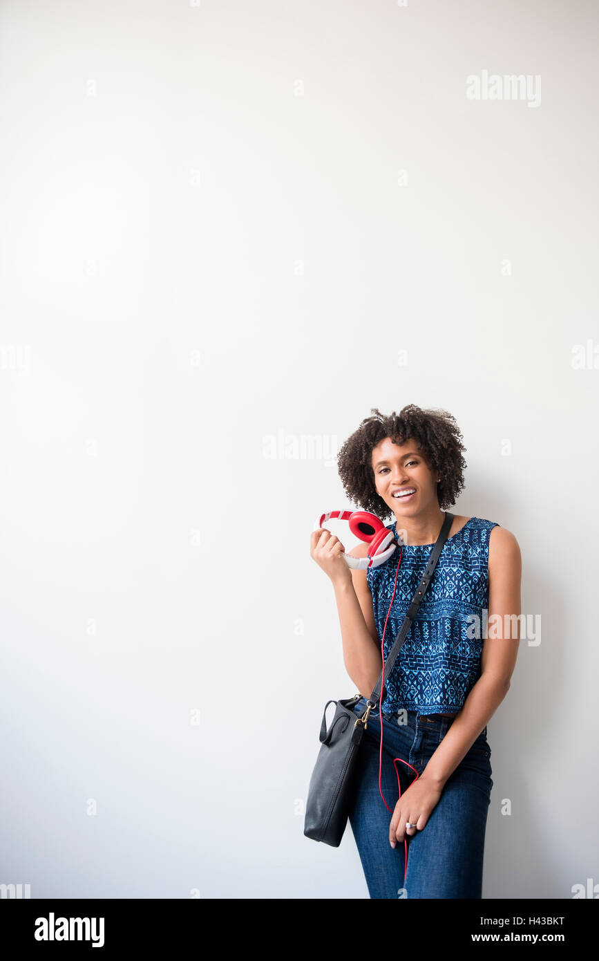 Schwarze Frau mit Handtasche halten Kopfhörer Stockfoto