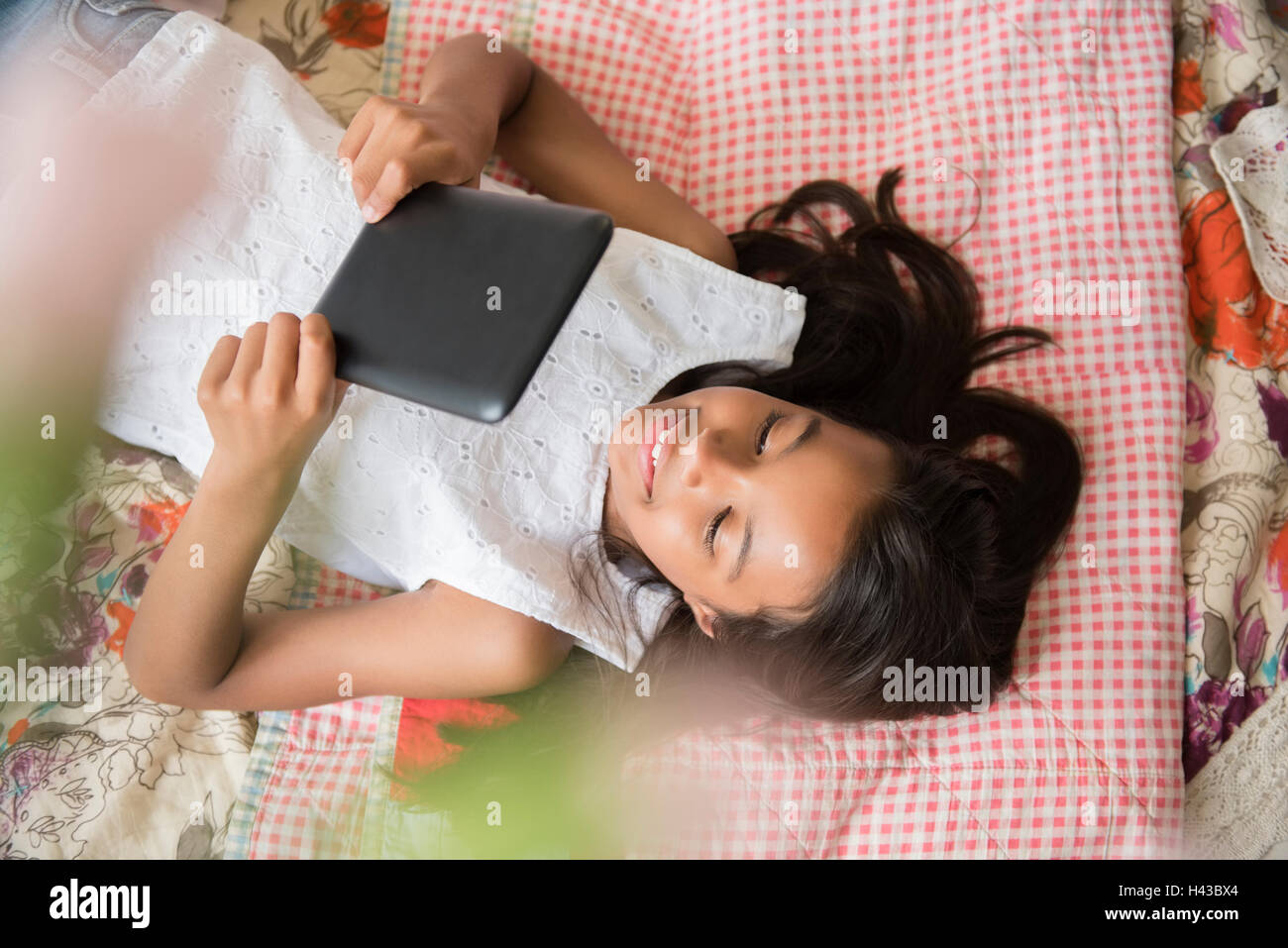 Gemischte Rennen Mädchen auf Bett mit digital-Tablette Stockfoto