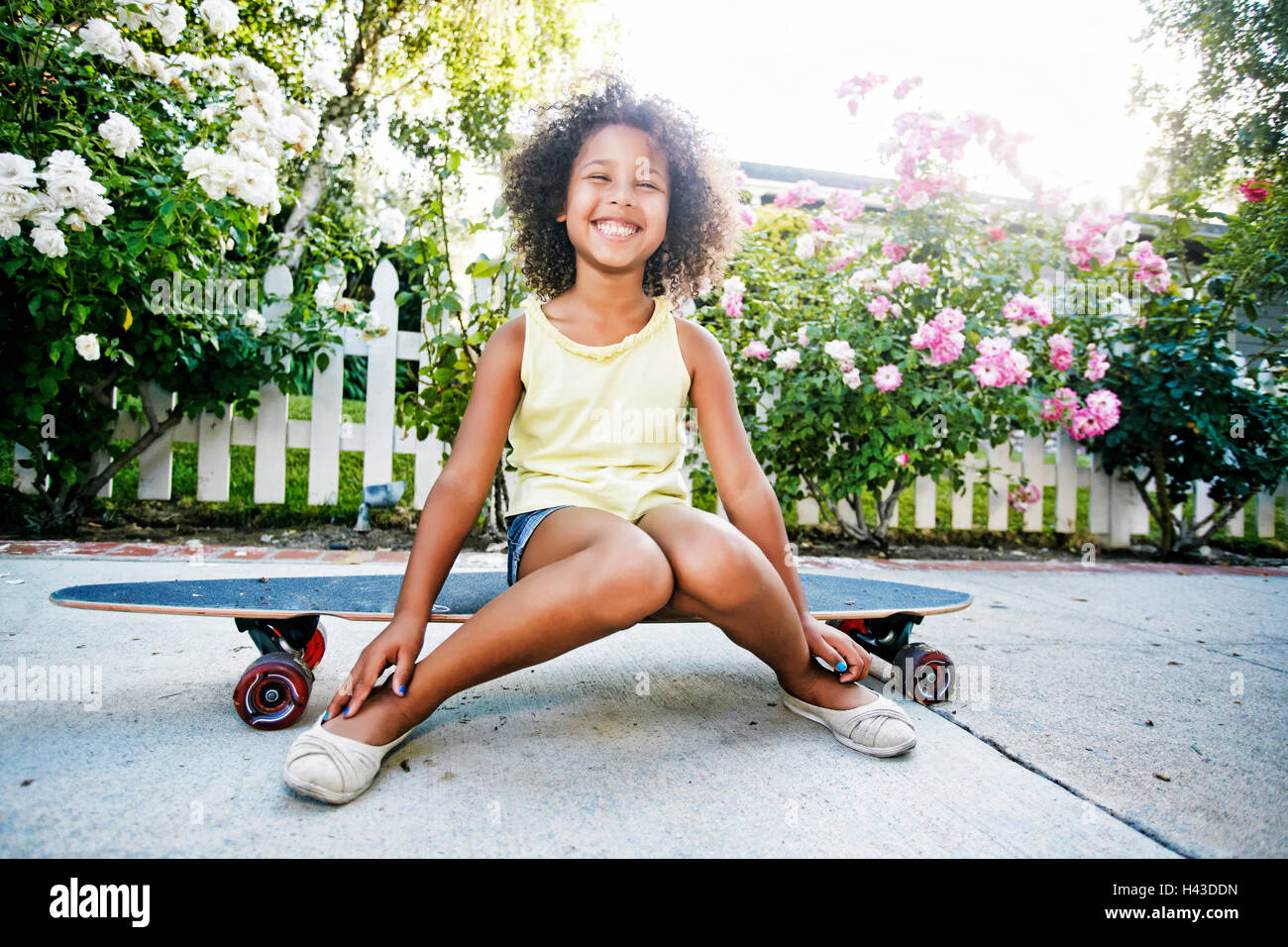 Lächelnd Mischlinge Mädchen sitzen auf skateboard Stockfoto