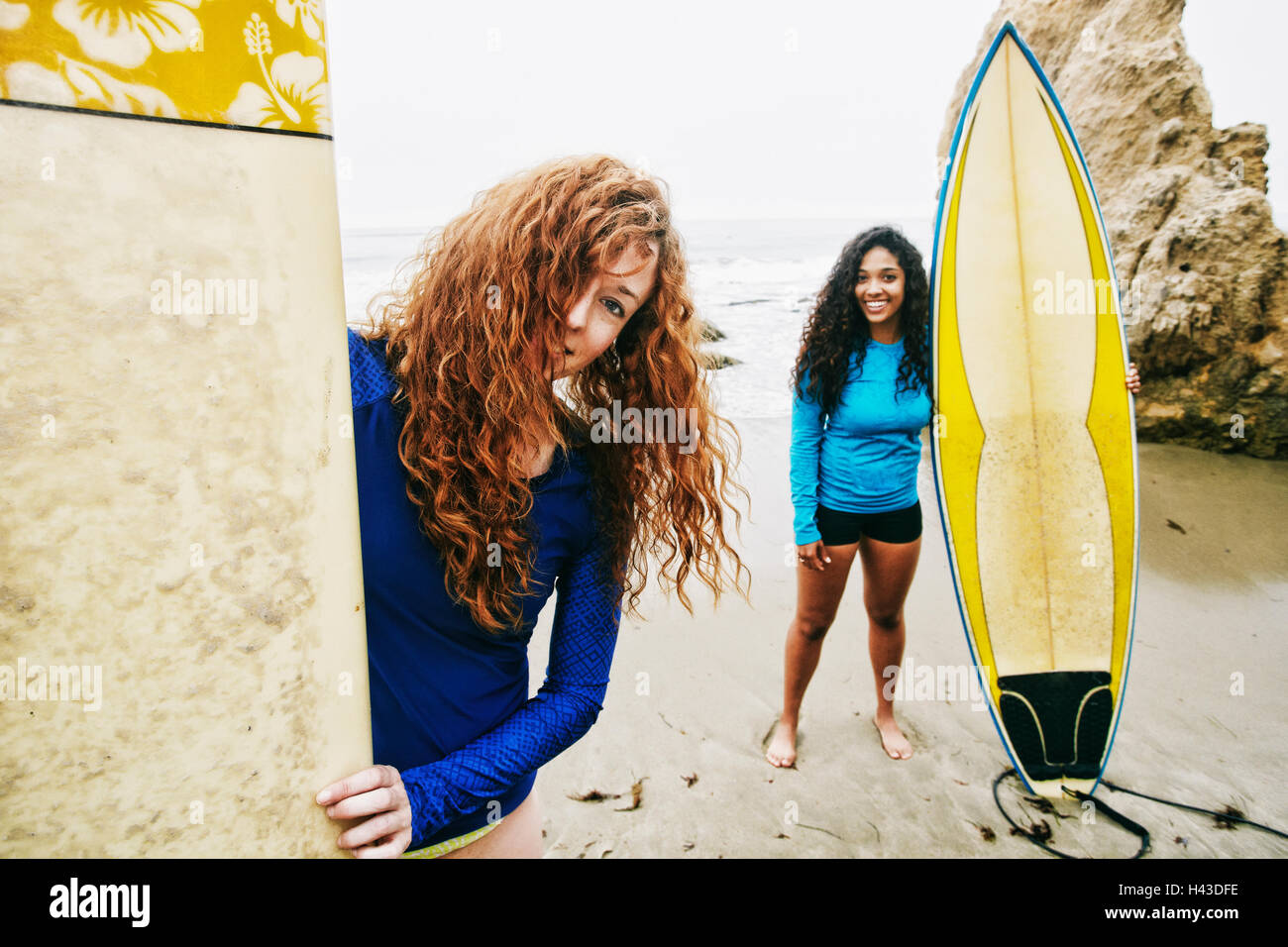 Lächelnde Frauen Surfbretter am Strand Stockfoto