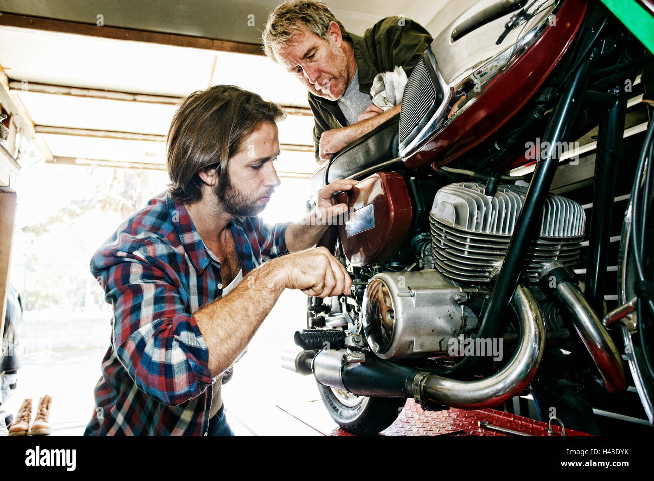 Kaukasische Vater beobachtete Sohn Reparatur Motorrad in garage Stockfoto