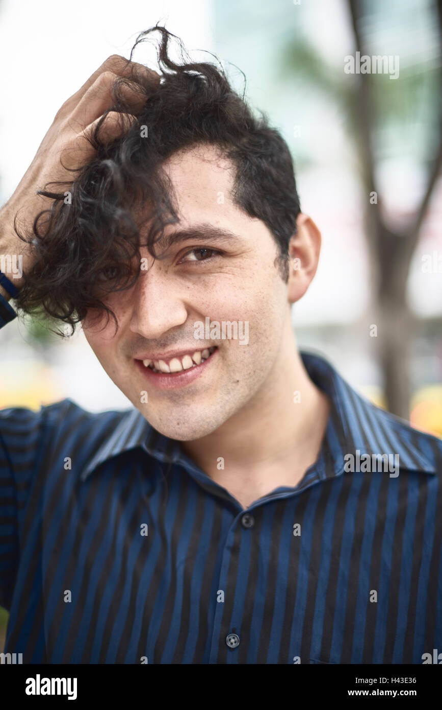 Lächelnder Hispanic Mann mit Hand im Haar Stockfoto