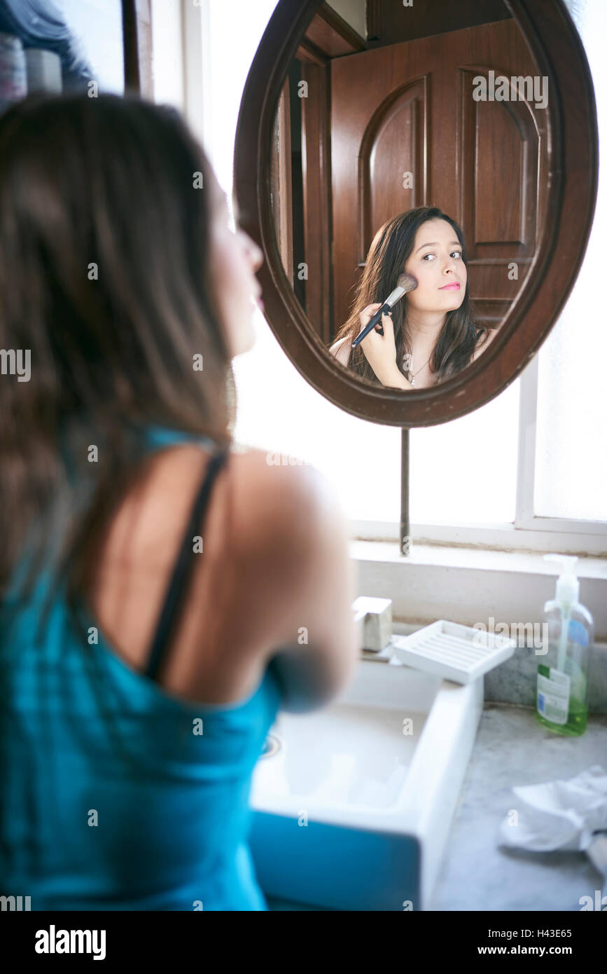 Hispanic Frau mit Make-up Pinsel in Spiegel Stockfoto