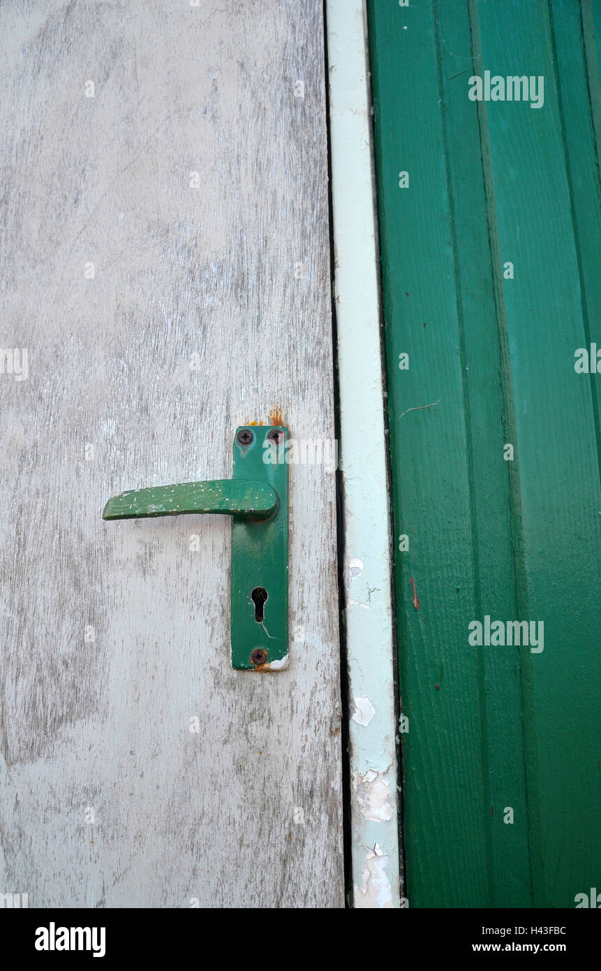 Nahaufnahme von einer grünen gewellte Wand mit einer weißen ungepflegt bemalten Tür mit einem grünen Türgriff. Stockfoto