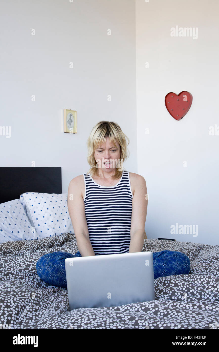 Überrascht kaukasischen Frau mit Laptop am Bett Stockfoto