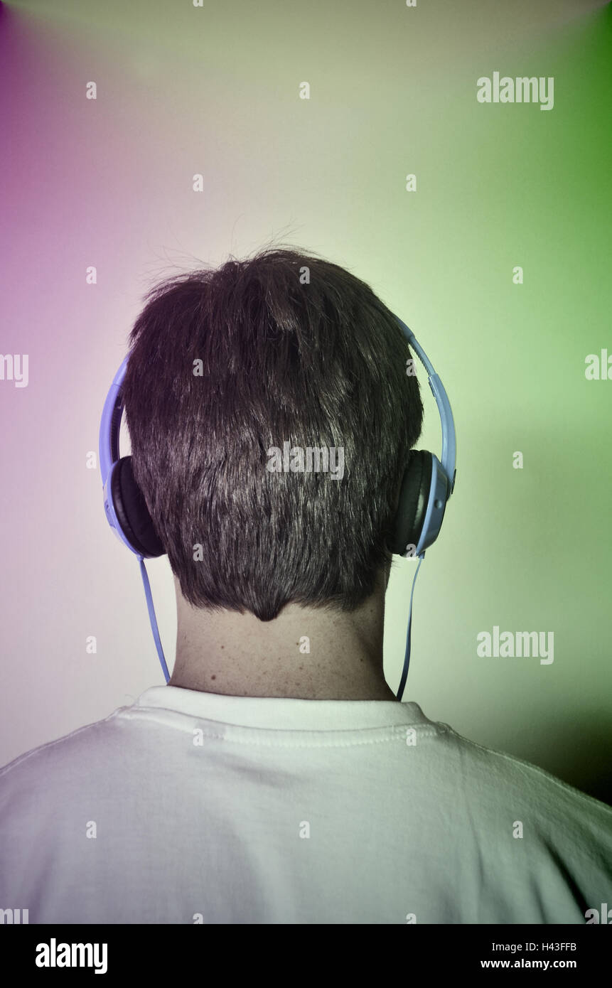 Ein Teenager von hinten gesehen hört Musik über Kopfhörer. Stockfoto