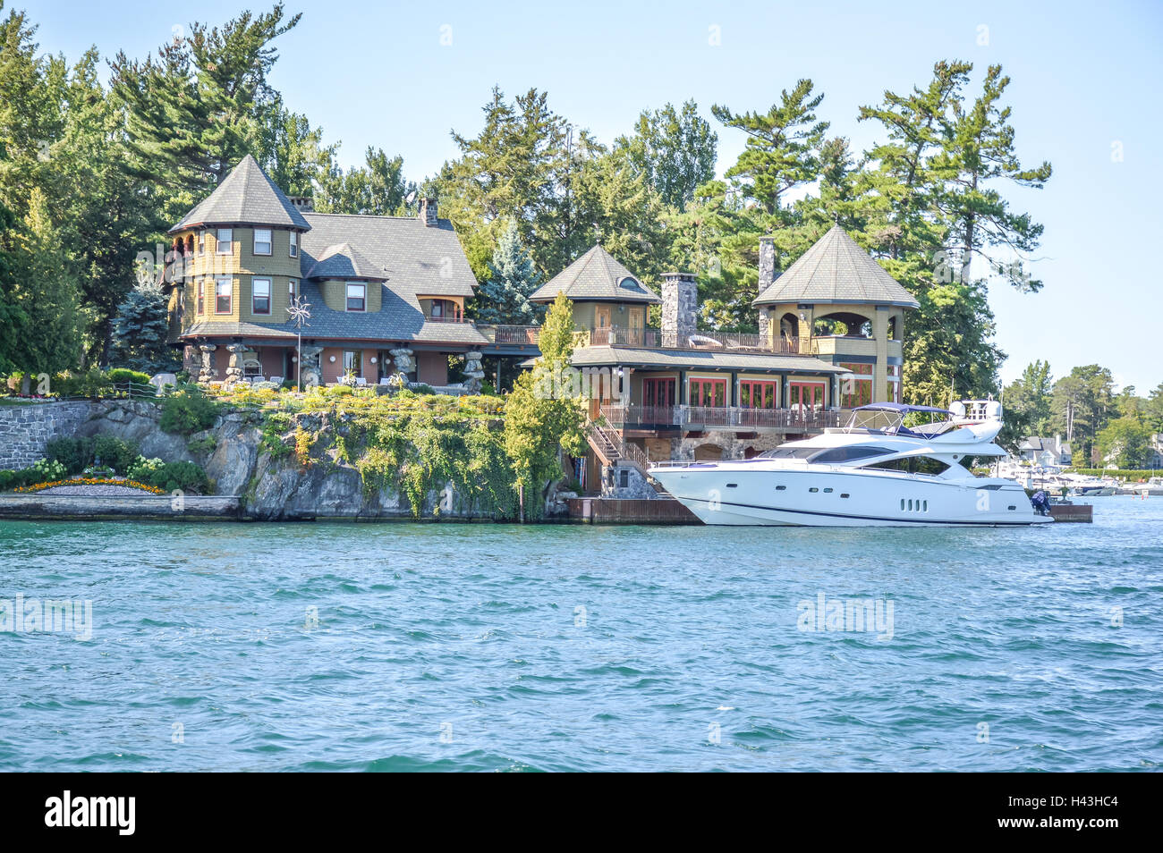 Eine Insel mit dem weißen Haus mit einem weißen Boot in Thousand Islands Region im Sommer in Kingston, Ontario, Kanada Stockfoto
