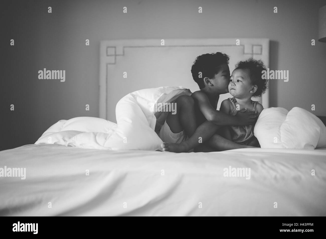 Bruder seine Schwester zu küssen auf die Wange, am Bett sitzen Stockfoto
