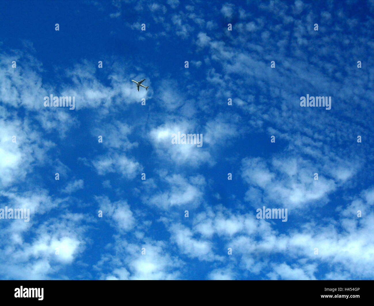 Flugzeug in kleinen Wolken am Himmel an einem sonnigen Nachmittag überqueren Stockfoto