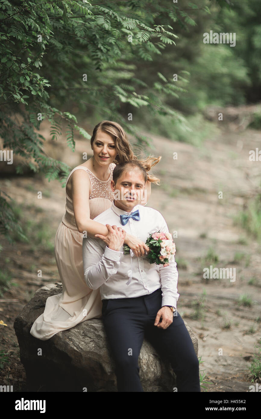 Elegante sanfte stilvolle Bräutigam und die Braut in der Nähe Fluss mit Steinen. Hochzeitspaar in der Liebe Stockfoto