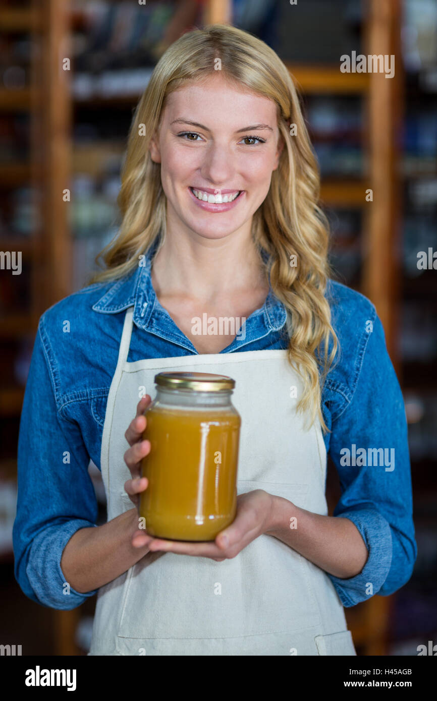 Weibliche Personal halten Glas Honig im Supermarkt Stockfoto