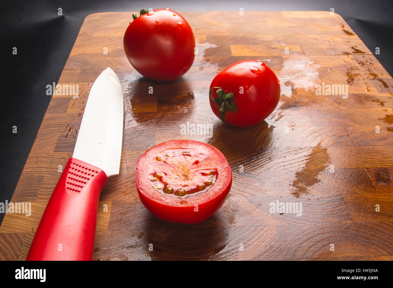 Stillleben - kleine reife Tomaten und Messer auf Holz Hintergrund Stockfoto