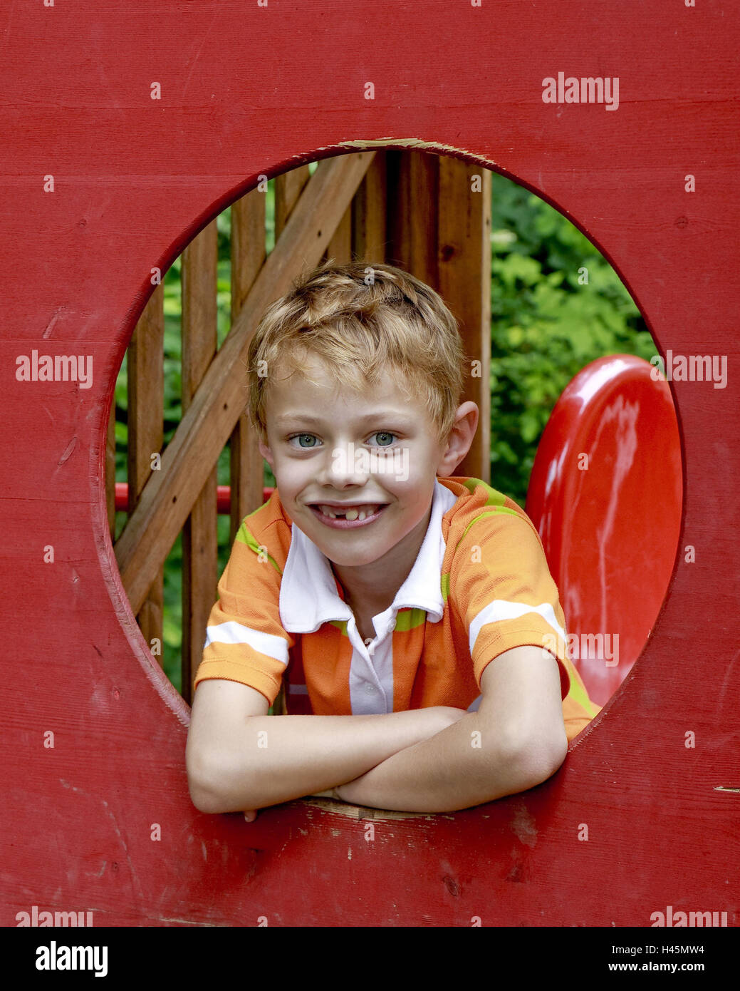 Ein Junge, 7 Jahre alt, auf einem Spielplatz, sieht durch eine Öffnung, Portrait, Modell veröffentlicht, Stockfoto
