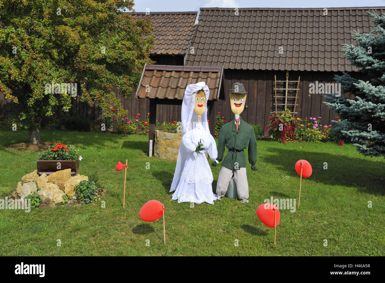 Holzhütte, Garten, Vogelscheuchen, Wiese, Vogelscheuche paar, Kleidung, Pflege, Anzug, Brautkleid, Besen, Puppen, "Brautpaar", erschrecken entfernt, Abschreckung, Luftballons, rot, Hütte, Bäume, Obstbaum, Tanne, Blumen, Sonnenschein, Stockfoto