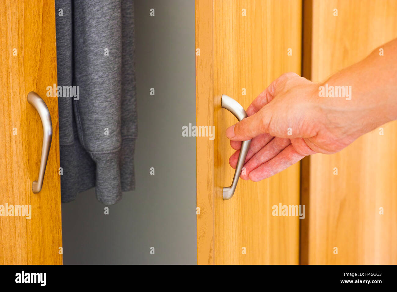 Hand der Person öffnen der Schranktür mit Kleidung Stockfoto