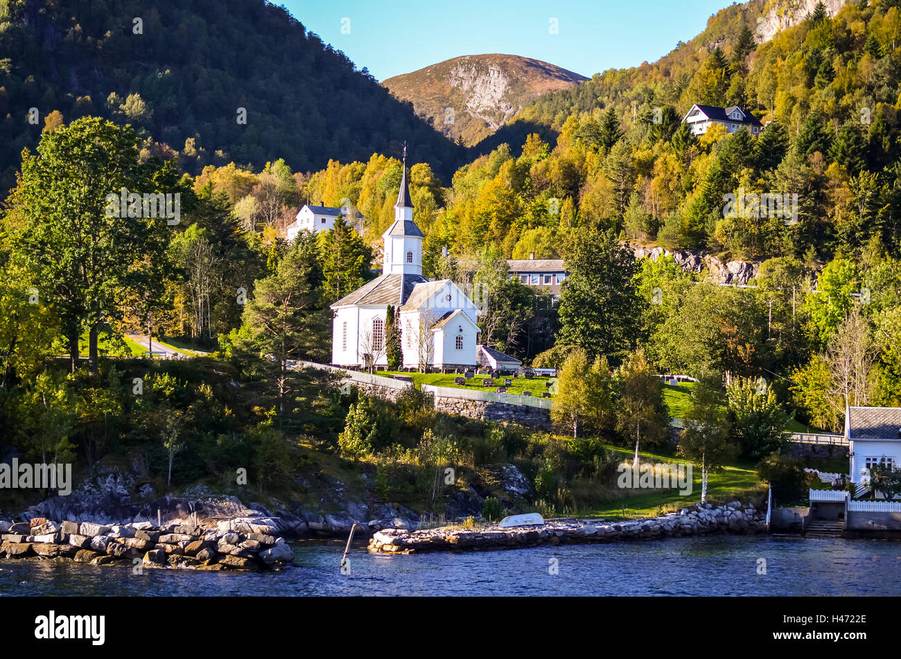 weiße Stabkirche im kleinen Dorf am Fjord Küstenblick vom Boot Stockfoto