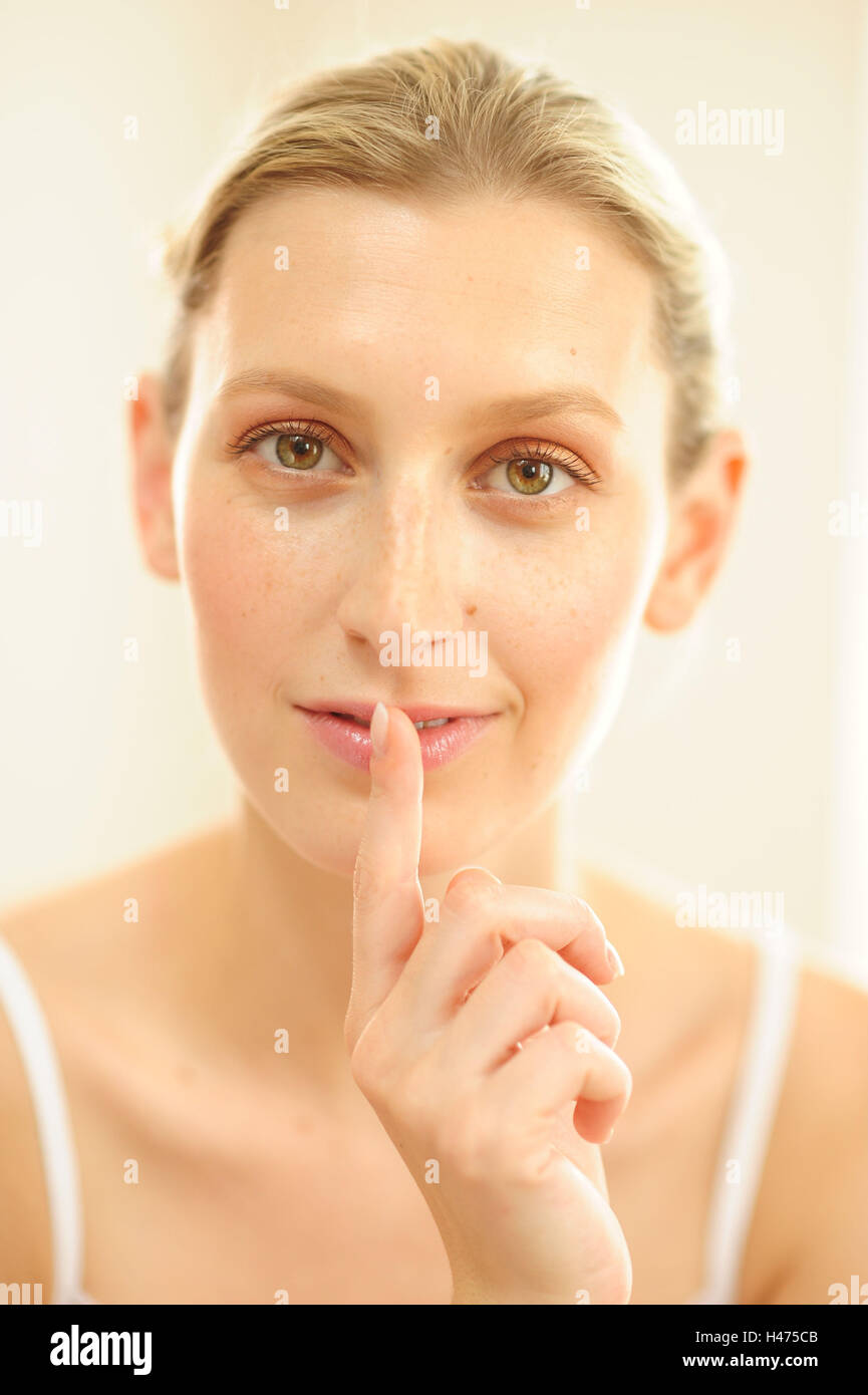 Junge Frau mit Finger in den Mund, Stockfoto