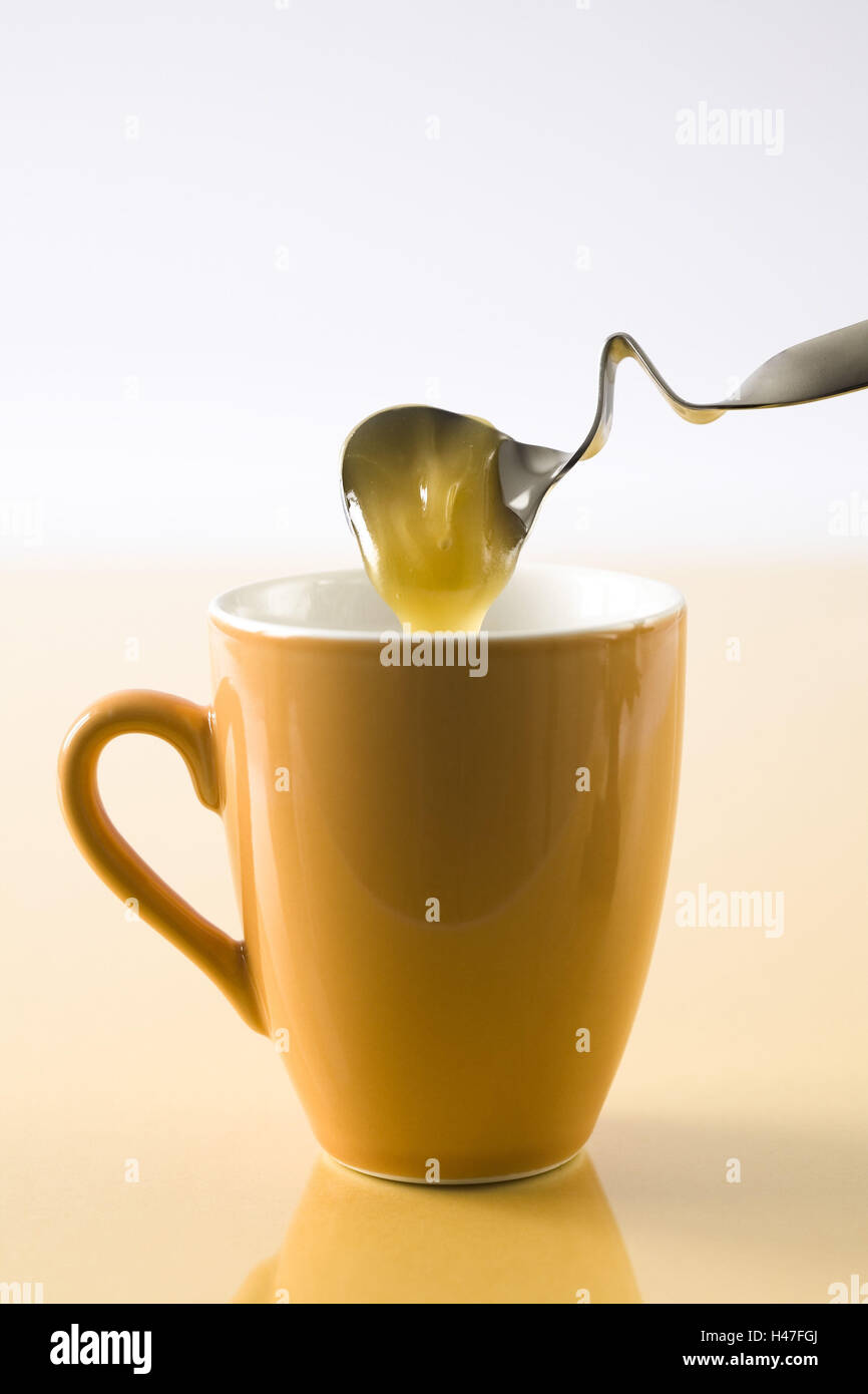 Schmier-Honig vom Löffel Honig fließt in die Tasse, Stockfoto