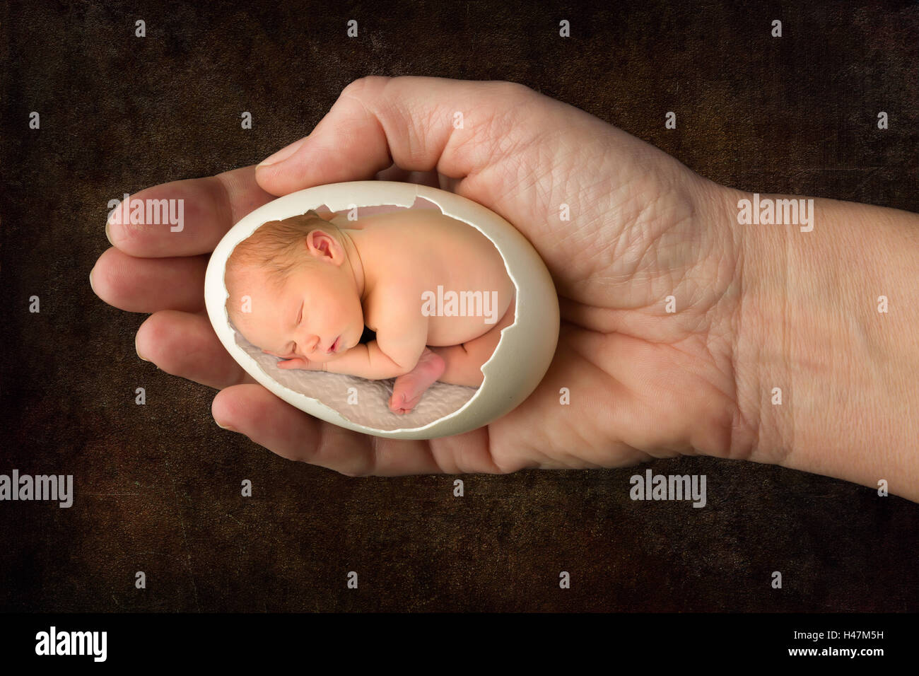 Neugeborene schlafen in einem gebrochenen Ei statt durch die Hand einer Frau Stockfoto