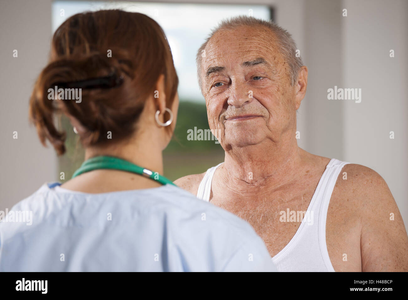 Krankenschwester kümmert sich um einen älteren Mann, Stockfoto